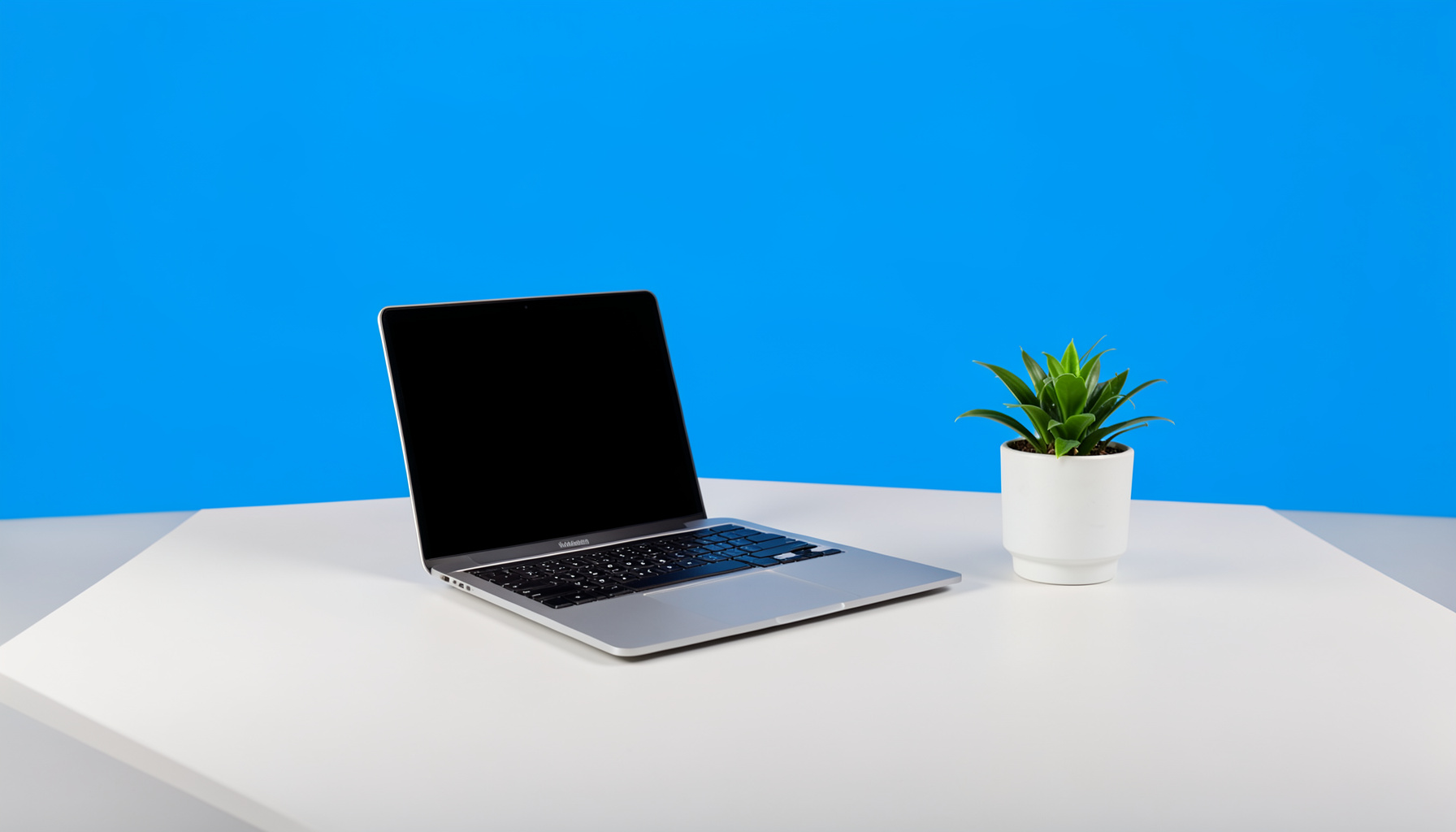 A clean studio photograph of a modern office desk with a laptop and a small plant, suggesting a telework environment on a neutral light-gray backdrop