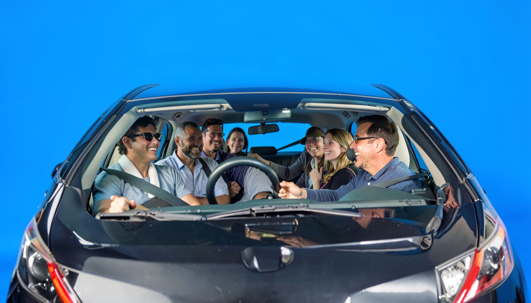 A group of people carpooling in a sedan, smiling and chatting on a sunny morning commute.